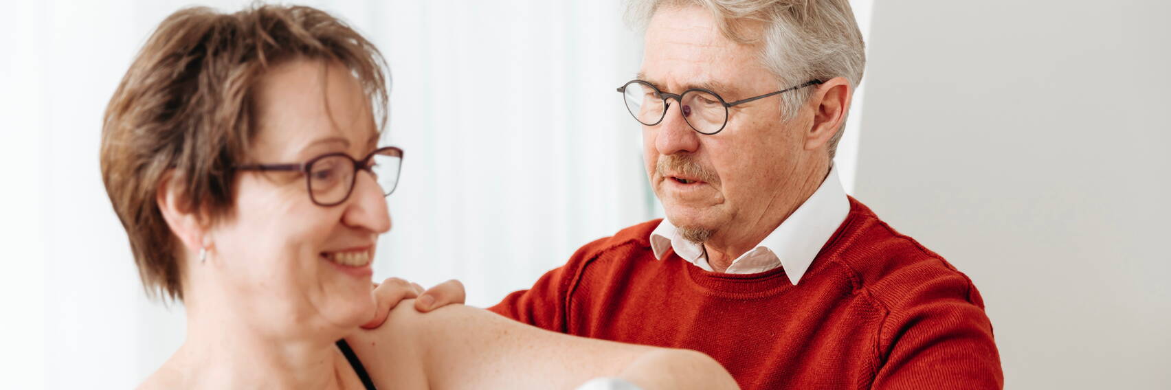 Chiropraktor bei Behandlung von Pateintin. Patientin lächelt.